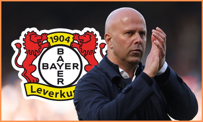Arne Slot claps his hands with Bayer Leverkusen club crest behind him.