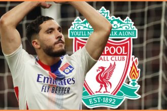 Rayan Cherki poses with his arms in the air in front of Liverpool club crest.