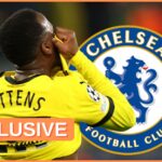 Jamie Gittens pulls his shirt over his face next to Chelsea club crest.