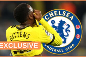 Jamie Gittens pulls his shirt over his face next to Chelsea club crest.