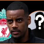 Alexander Isak looks on in front of Liverpool club crest.