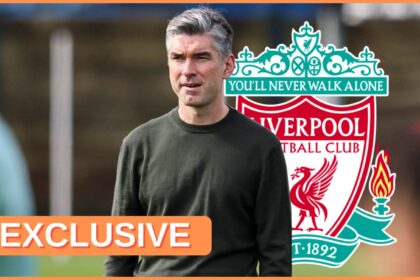 Richard Hughes looks on next to Liverpool club crest.