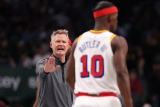 Golden State Warriors head coach Steve Kerr speaks with No. 10 Jimmy Butler during the second half of a game against the Dallas Mavericks at American Airlines Center on February 12, 2025 in Dallas, Texas.