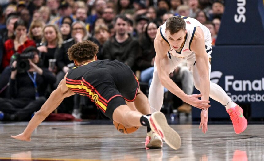 Christian Braun (0) of the Denver Nuggets and Dyson Daniels (5) of the Atlanta Hawks compete for a loose ball at Ball Arena during the second quarter.