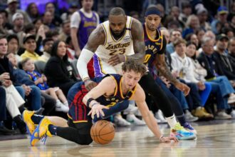 Golden State Warriors player Brandin Podzemski looks for a loose ball alongside Gary Payton II during a game against LeBron James.