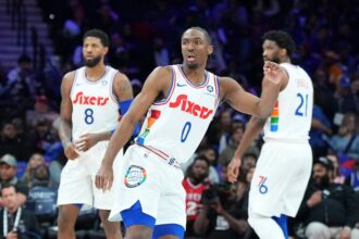 Tyrese Maxey #0, Paul George #8, and Joel Embiid #21 of the Philadelphia 76ers watch the matchup against the Toronto Raptors at the Wells Fargo Center.