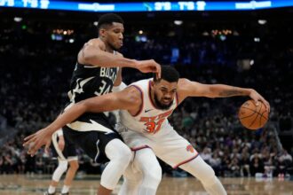 Karl-Anthony Towns #32 of the New York Knicks dribbles the ball against #34 Giannis Antetokounmpo of the Milwaukee Bucks during the third quarter at Fiserv Forum.