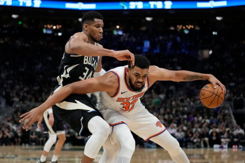 Karl-Anthony Towns #32 of the New York Knicks dribbles the ball against #34 Giannis Antetokounmpo of the Milwaukee Bucks during the third quarter at Fiserv Forum.